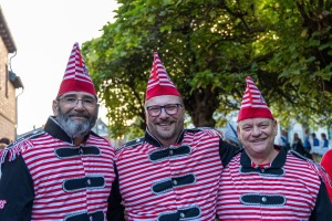 Das designierte Dreigestirn in rot-weißen Jacken und Mützen lächelt in die Kamera, Köln-Weiß